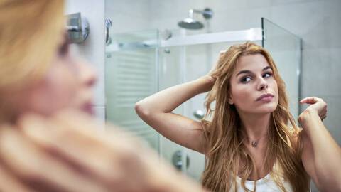 photo of woman with wavy hair looking in mirror