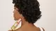 Woman with curly brown hair holding a bottle of Everpure Bonding Serum