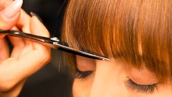 photo of woman getting bangs trimmed by stylist