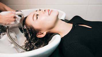 photo of woman getting hair shampooed in sink