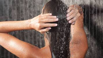 photo of woman rinsing hair in shower