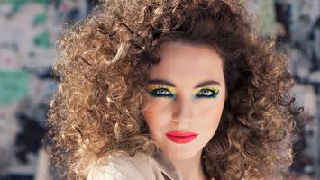 photo of woman with big curly hair and vibrant makeup