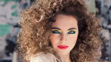 photo of woman with big curly hair and vibrant makeup