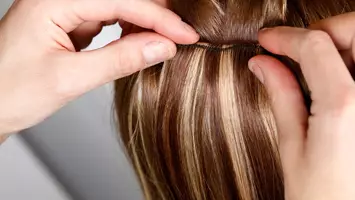 close up of stylist applying hair extensions