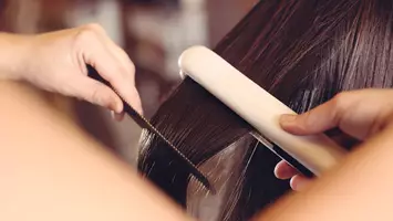 photo of woman using flat iron on hair