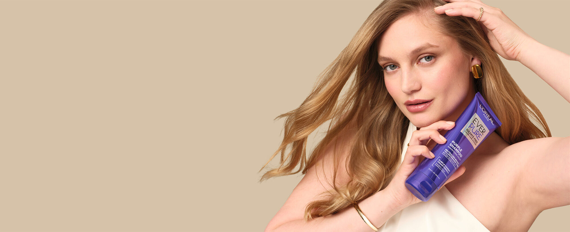 Woman with blonde hair holding L’Oreal Paris Purple Shampoo