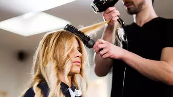photo of hair stylist blowing out woman's hair