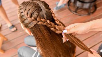 woman styling half braided ponytail hairstyle on long hair