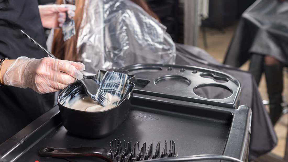 photo of stylist applying bleach to hair