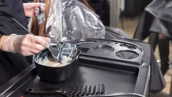 photo of stylist applying bleach to hair