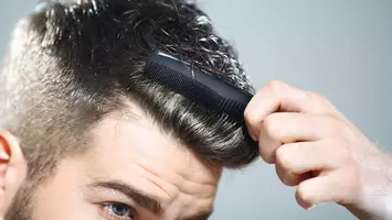 close up of man styling hair with comb