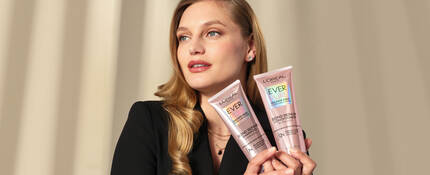 Woman with blonde hair and with two bottles of L'Oreal Paris shampoo and conditioner