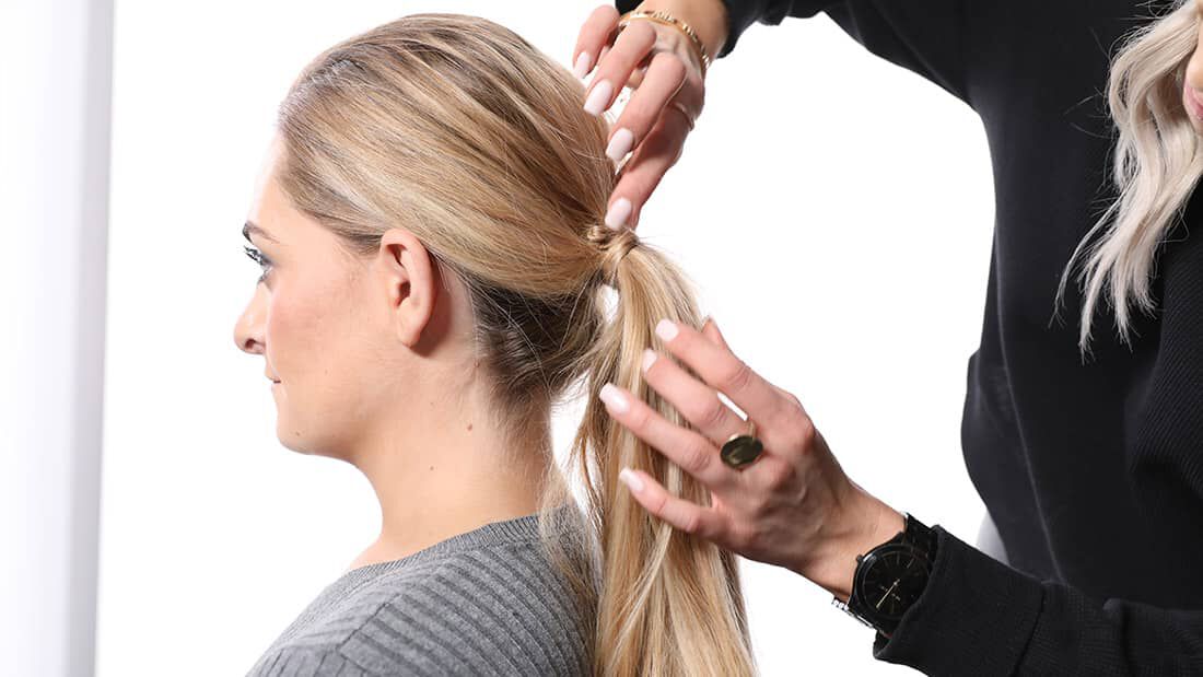 photo of stylist demonstrating how to style a low ponytail
