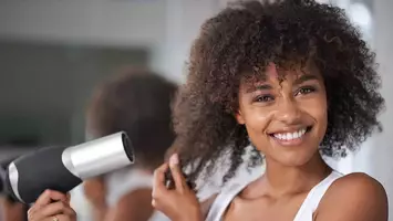 woman blowdrying her curly hair