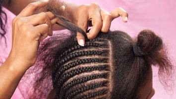 photo of woman getting braids done on hair