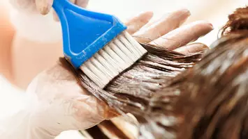 close up photo of stylist applying color to hair