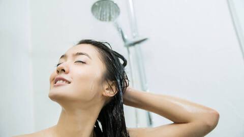 woman rinsing hair in shower with cleansing conditioner