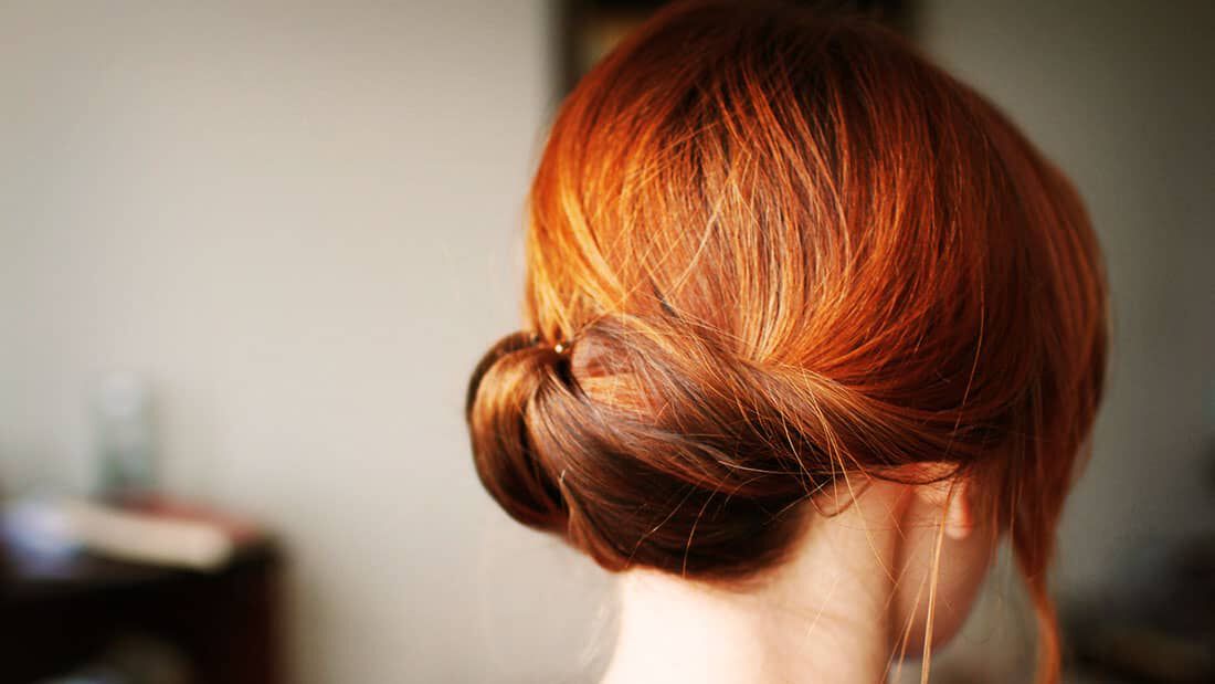 woman with balayage red hair in a bun
