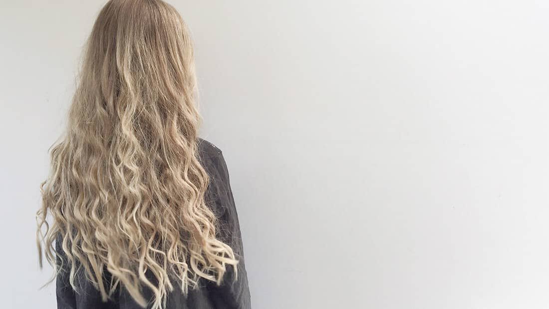 photo of woman with long wavy blonde hair pureology beach waves sugar spray