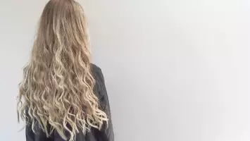 photo of woman with long wavy blonde hair pureology beach waves sugar spray