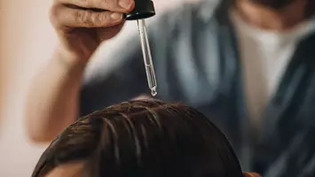 photo of stylist applying tea tree oil on women's scalp