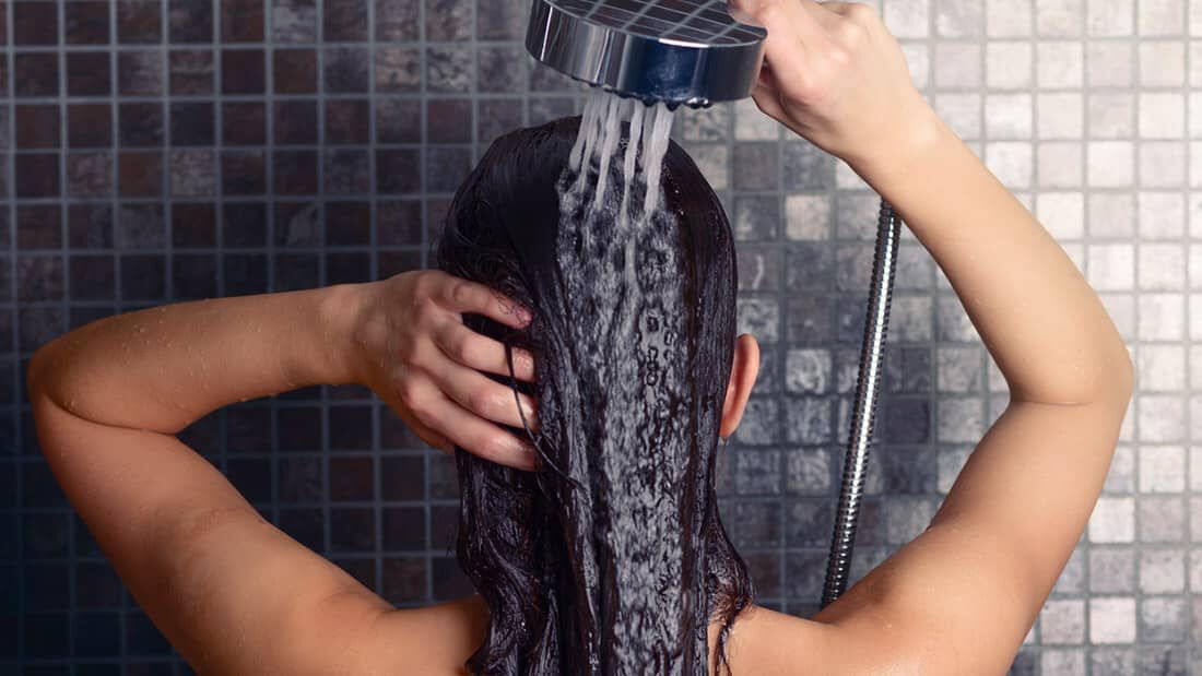 photo of woman rinsing shampoo in the shower