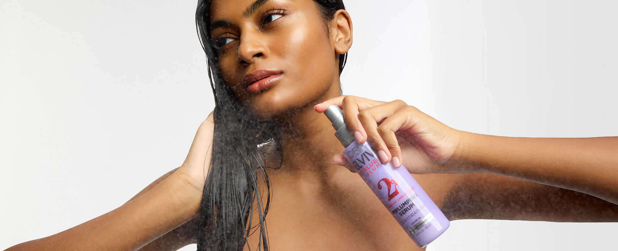 Brunette woman holding a bottle of L'Oreal Paris serum