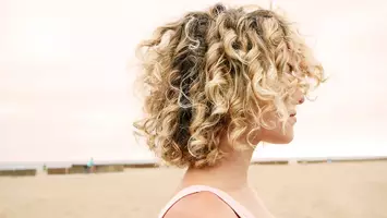 woman with blonde curly hair on a beach