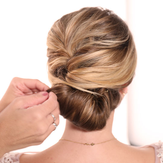 hand pinning bun in woman's updo