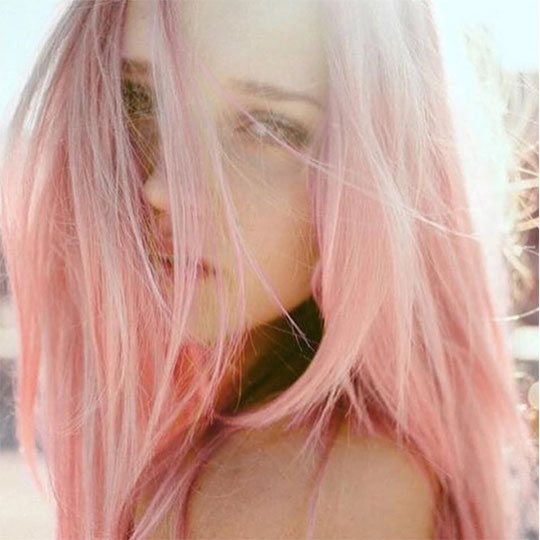 woman looking through windblown peach hair color