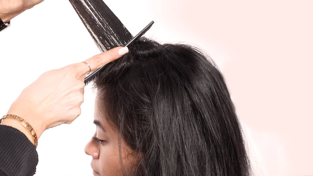 Close-up of hairstylist cutting wet hair in a salon.