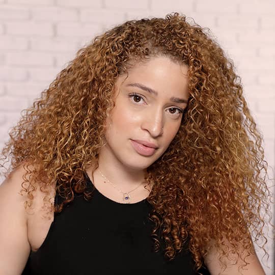woman with red curls looking at camera showing hairline