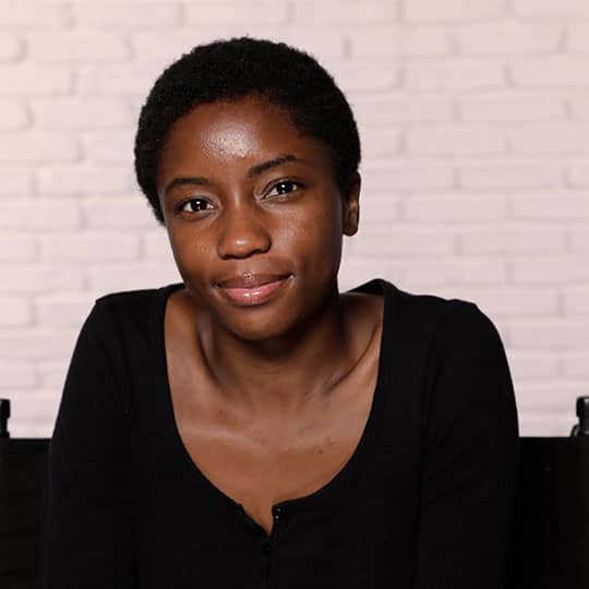 black woman with short hair smiling at camera and showing hairline